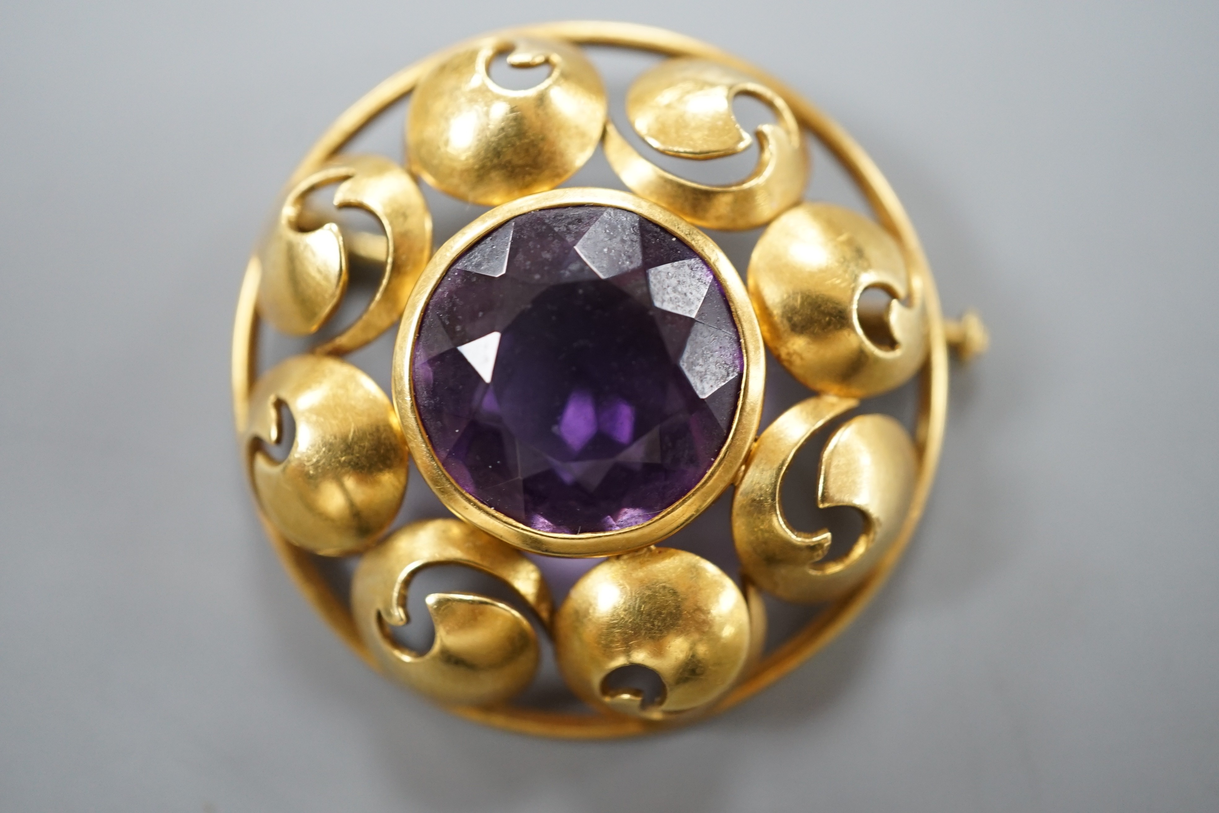 A continental 750 yellow metal circular amethyst set circular brooch, 31mm, gross weight 12.2 grams.